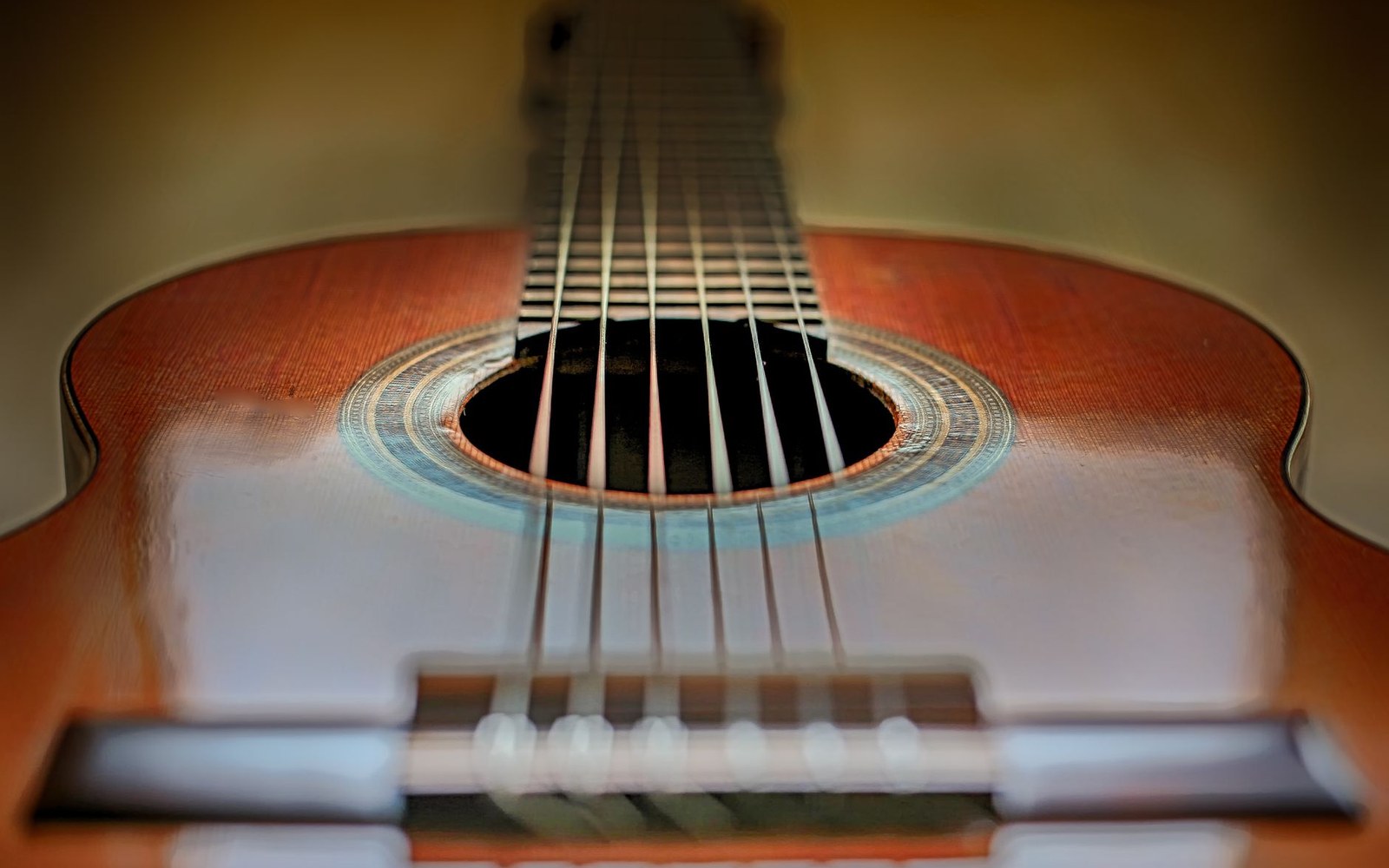 Close-up of a classical guitar's soundhole, bridge and strings in shallow focus