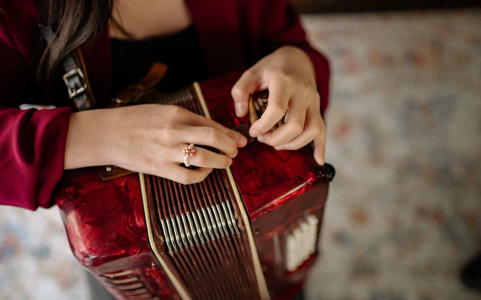 A woman's hands rest on the keys and bellows of a red accordion