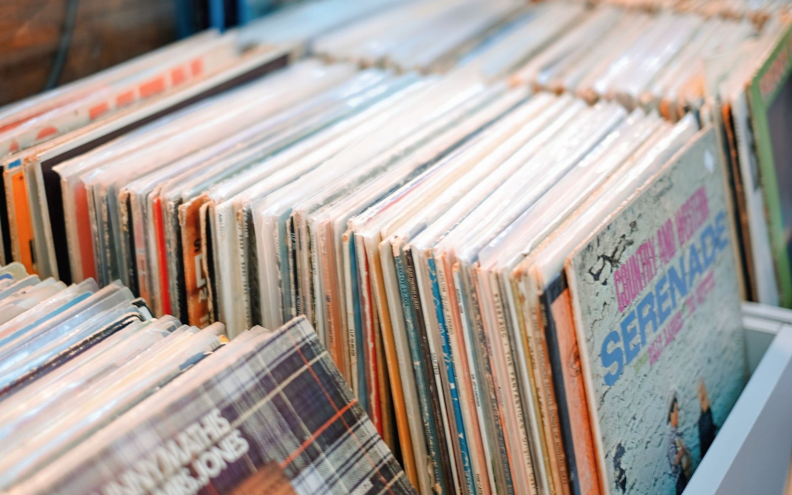 Record-shop rack with Latin album sleeves displayed face-out under fluorescent light